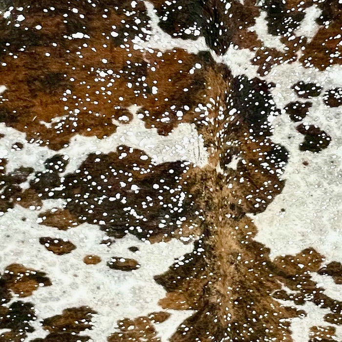 Closeup of this XL Colombian Tricolor Cowhide, showing white with black and brown speckles and spots, and a silver, metallic acid wash (COAW511)