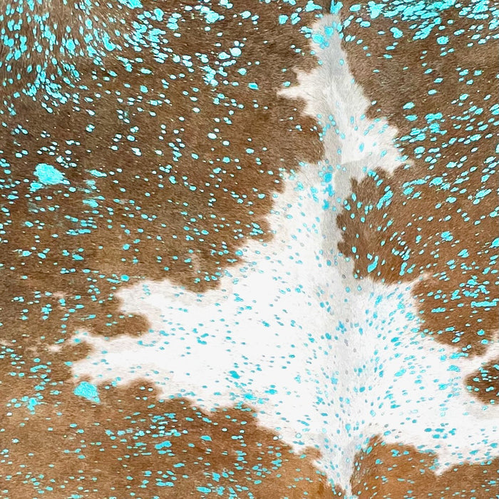 Closeup of this Large Colombian Cowhide, showing white with large and small, brown spots, and a metallic, turquoise acid wash COAW517)