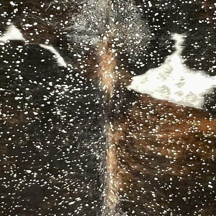 Closeup of this Colombian Dark Tricolor Cowhide, black with some brown and white spots, and a metallic, silver acid wash COAW520)