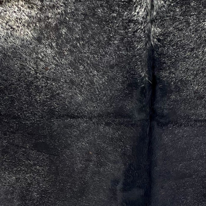 Closeup of this Speckled Colombian Cowhide, showing mostly solid black, and white speckles and spots on part of the shoulder (COBKW278)