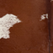 Closeup of this Brazilian Cowhide, showing dark reddish brown with white spots that have dark reddish brown speckles (BRBNW407)
