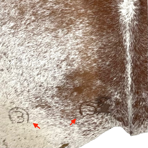 Closeup of this XL, Brown and White, Speckled, Brazilian Cowhide, showing two brand marks on the butt, on the left side (BRSP2168)