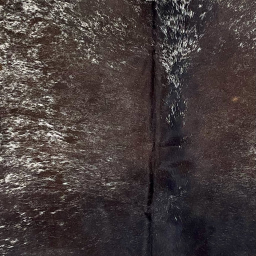 Closeup of this Speckled Brazilian Cowhide, showing dark chocolate, with some white speckles, down the middle, and white with dark chocolate speckles and spots on part of the shoulder  (BRSP3261)