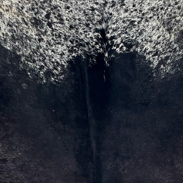 Closeup of this Speckled Brazilian Cowhide, showing mostly solid black on the back, and white with black speckles and spots on the shoulder (BRSP3721)