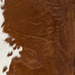 Closeup of this Calfskin, showing mostly solid reddish brown and small white spots on the belly (CALF919)