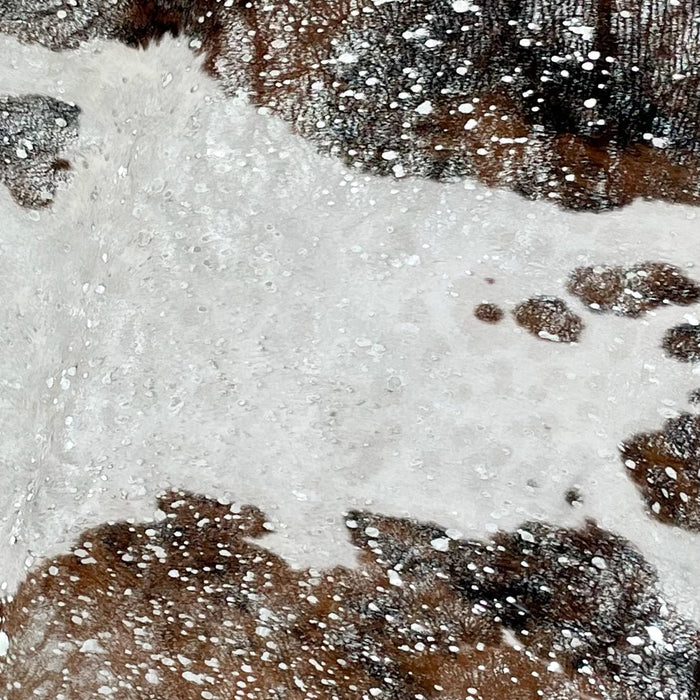 Closeup of this Colombian Tricolor Cowhide, showing white with spots that are brown and black, and a silver, metallic acid wash (COAW448)