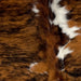 Closeup of this Colombian, Tricolor Cowhide, showing a brown and black, brindle pattern, with a few white spots on the back and down the spine (COTR1024)