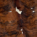 Closeup of this Colombian Tricolor Cowhide, showing a reddish brown and black, brindle pattern, with a few small, white spots (COTR1026)