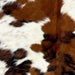 Closeup of this Colombian Tricolor Cowhide, showing long hair that is white with faint, black and reddish brown speckles, and large and small spots that are black, reddish brown, or a mix of black and reddish brown (COTR1442)