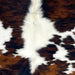 Closeup of this Large Colombian Tricolor Cowhide, showing white with large and small spots that have a reddish brown and black, brindle pattern (COTR1464)