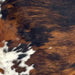 Closeup of this Large Colombian Tricolor Cowhide, showing a black and brown, brindle pattern, and white with brown and black spots on the belly (COTR1476)