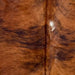 Closeup of this Large Colombian Tricolor Cowhide, showing a reddish brown and black, brindle cowhide, and a white spot down the middle (COTR1527)