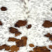 Closeup of this Colombian Speckled Tricolor Cowhide, showing white with faint, brown and black speckles, and small spots that have a mix of reddish brown and black  (COTR1580)