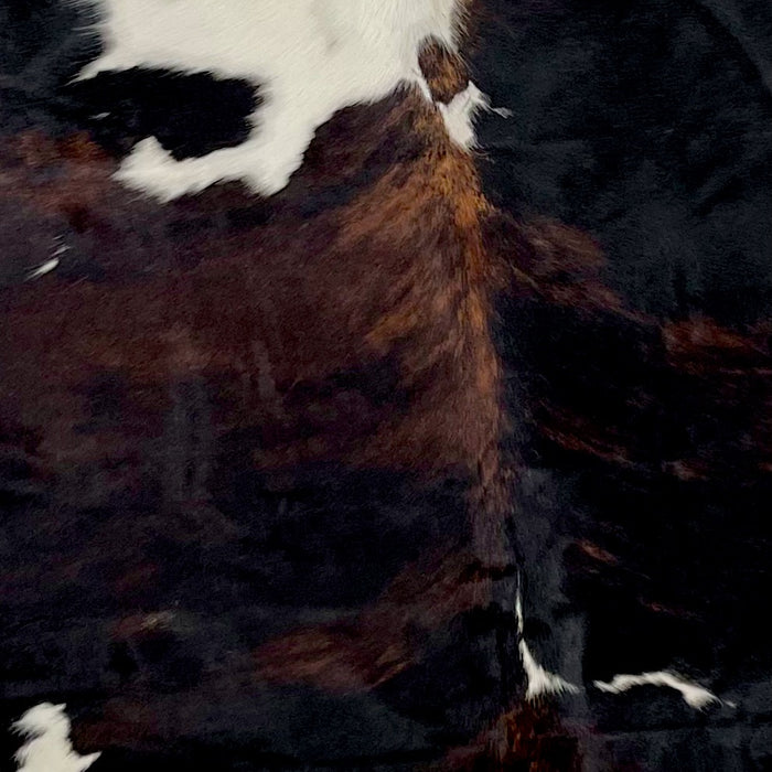 Closeup of this Colombia,n Dark Tricolor Cowhide, showing a mix of black and dark, red brown, and one large and a couple small, white spots down the middle (COTR944)