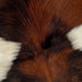 Closeup of this Tricolor Mini Cowhide, showing a mix of red brown and black, and a large, white spot on the left side and one of two smaller white spots on the right side (MINI218)
