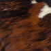 Closeup of this Tricolor Mini Cowhide, showing a reddish brown and black, brindle pattern, with a few small, white spots (MINI241)