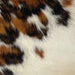 Closeup of this Tricolor Mini Cowhide, showing a brown and black brindle pattern, and off-white, with brown and black spots, on the lower right side (MINI245)