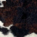 Closeup of this Tricolor Mini Cowhide, showing curly hair that has a mix of black and dark brown, and white across the bottom part of the hide (MINI291)