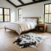 Tricolor cowhide rug CH-032 at the foot of a bed in a bright modern farmhouse bedroom with shiplap walls and white linen bedding
