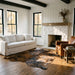 Tricolor cowhide rug CH-006 in a modern farmhouse living room by a whitewashed stone fireplace, with a linen sofa and leather armchair