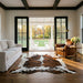 Tricolor cowhide rug CH-096 in a modern farmhouse living room with shiplap walls, black French doors to a porch, linen sofa and leather armchair