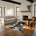 Tricolor cowhide rug CH-016 in a modern farmhouse living room by a whitewashed stone fireplace, with a linen sofa and leather armchair