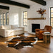 Tricolor cowhide rug CH-073 in a modern farmhouse living room by a whitewashed stone fireplace, with a linen sofa and leather armchair