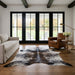 Grey and black salt and pepper cowhide rug in a modern farmhouse living room with black French doors, linen sofa and leather club chair
