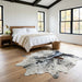 Salt and pepper Brazilian cowhide rug at the foot of a bed in a bright modern farmhouse bedroom with light oak floors