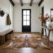 Brown salt and pepper cowhide rug on the oak floor of a modern farmhouse entry hall with a wooden bench and black front door