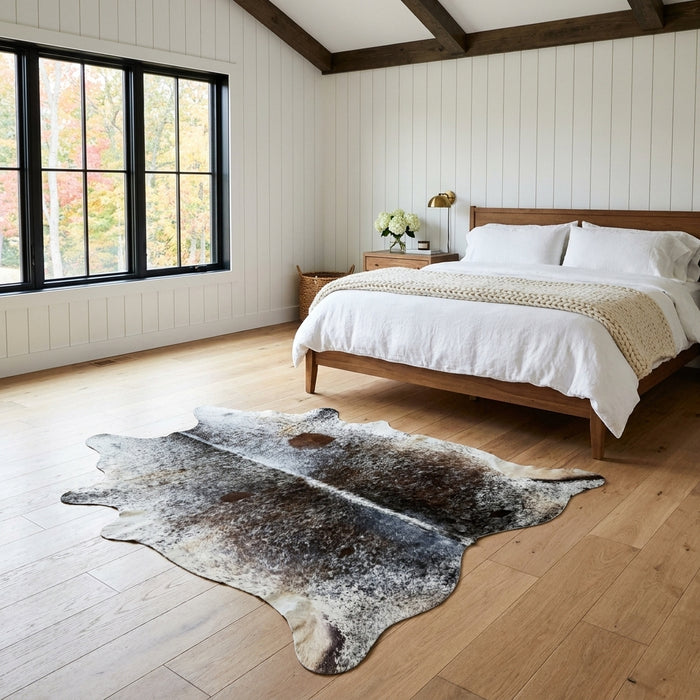 Black and brown speckled Brazilian cowhide rug in a bright modern farmhouse bedroom with light oak floors