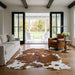 Brown and white cowhide rug in a farmhouse living room with French doors open to a covered porch