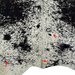 Closeup of this XL, Off-White and Black, Brazilian, Speckled Cowhide, showing one brand mark in the middle of the hide, along the spine, one on the lower left side, and another on the right side, along the lower edge (BRSP1695)